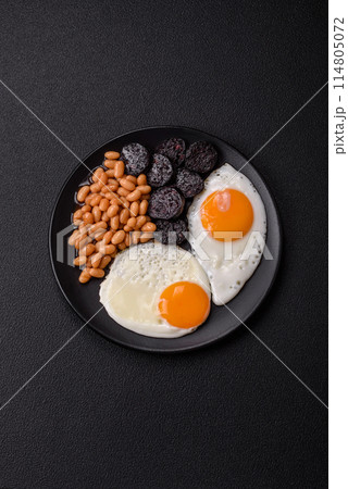 English breakfast with fried eggs, bacon, beans, tomatoes, spices and herbs 114805072