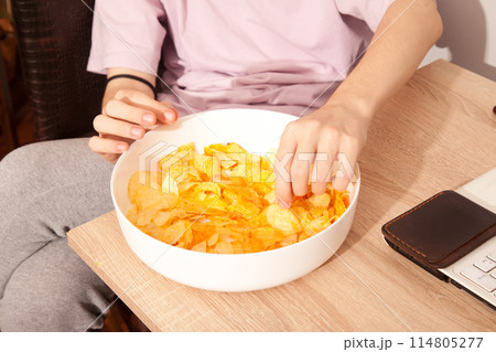 Caucasian person in pink t-shirt holding plate full of potato chips and preparing to eat Caucasian person in pink t-shirt holding plate full of potato chips and preparing to eat 114805277