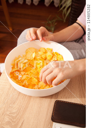 Caucasian person in pink t-shirt holding plate full of potato chips and preparing to eat Caucasian person in pink t-shirt holding plate full of potato chips and preparing to eat 114805282