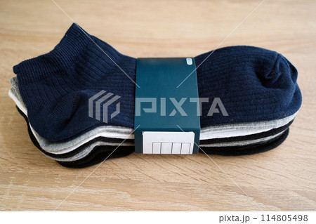 Package of multi-colored men's socks short, woven socks packaged, on a wooden floor 114805498