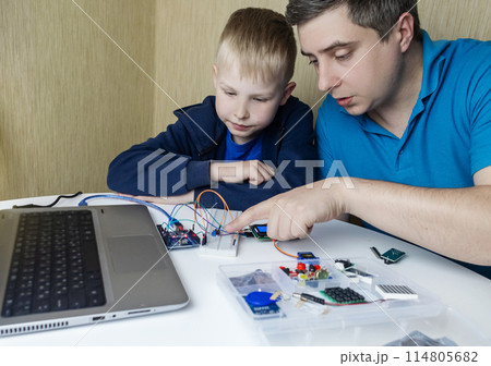 Programming for children. A teacher teaches a child at a robotics and IT school. Boy learning to code control board Programming for children. A teacher teaches a child at a robotics and IT school. Boy learning to code control board 114805682