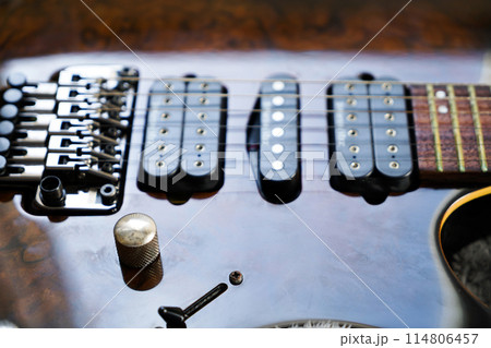 Electric guitar bridge, strings and pickup, detail close-up view of guitar pickup in wood walnut 114806457
