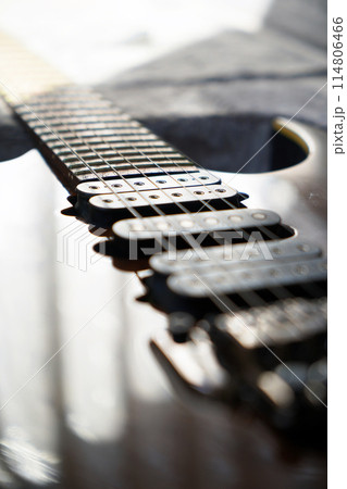 Electric guitar bridge, strings and pickup, detail close-up view of guitar pickup in wood walnut 114806466