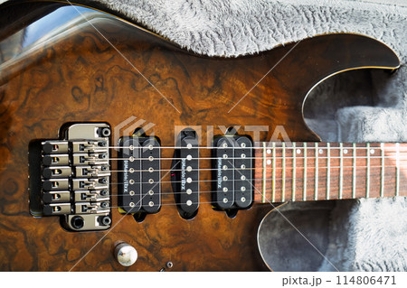 Electric guitar bridge, strings and pickup, detail close-up view of guitar pickup in wood walnut 114806471