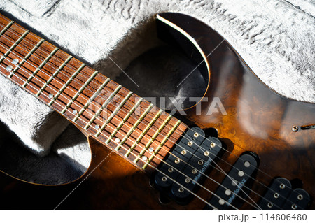 Electric guitar bridge, strings and pickup, detail close-up view of guitar pickup in wood walnut 114806480