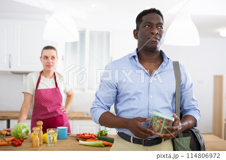 Man holds a jar of vegetables and salad prepared by his caring wife Man holds a jar of vegetables and salad prepared by his caring wife 114806972
