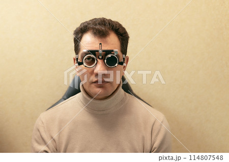 46-year-old man sits in refractive glasses to determine visual acuity and astigmatism 114807548
