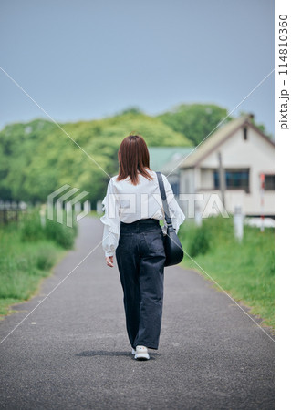川沿いを歩く若い女性の後ろ姿 114810360