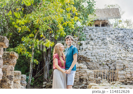 Couple, man and woman tourists at Coba, Mexico. Honeymoon Ancient mayan city in Mexico. Coba is an archaeological area and a famous landmark of Yucatan Peninsula. Cloudy sky over a pyramid in Mexico 114812626
