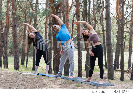 A group of three people doing exercises in the forest. 114813275