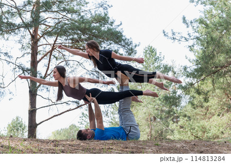 Three people standing in an elaborate acro yoga pose. 114813284