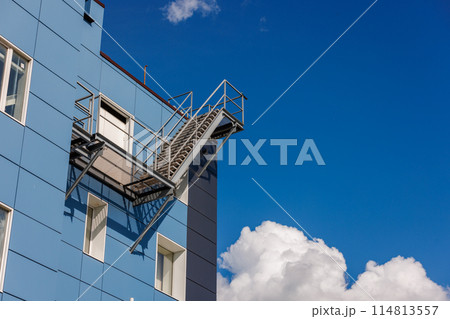 Azure building with a side fire escape, under a sky with fluffy clouds Azure building with a side fire escape, under a sky with fluffy clouds 114813557