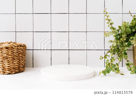 Marble white round podium for bathing products in bathroom front view, straw and green plant in pot 114813579