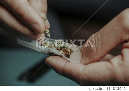 man putting some cannabis on a rolling paper man putting some cannabis on a rolling paper 114813941