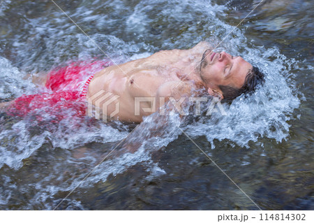 Man relaxing in mountain river. Healthy lifestyle. Calm man swimming in flowing water. Leisure activity. Beautiful man with closed eyes in waterfall. Breathtaking moment. Life balance. Man relaxing in mountain river. Healthy lifestyle. Calm man swimming in flowing water. Leisure activity. Beautiful man with closed eyes in waterfall. Breathtaking moment. Life balance. 114814302