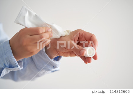 Hands in a blue shirt hold a tube of cream. Hands in a blue shirt hold a tube of cream. 114815606