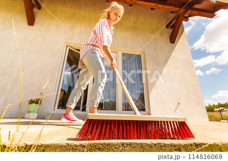 Woman cleaning patio using brush broom 114816069