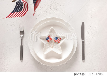 Patriotic table setting with American flag and decoration in national flag colors on white table. Independence Day. Happy Memorial Day. View from above. Patriotic table setting with American flag and decoration in national flag colors on white table. Independence Day. Happy Memorial Day. View from above. 114817086