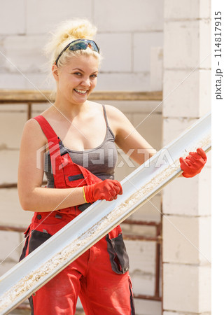 Woman carrying gutter on construction site 114817915
