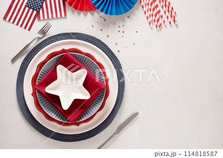 Patriotic table setting with american flag and decoration in national flag colors on white background. Independence Day. Happy Memorial Day. View from above. Copy space. 114818587