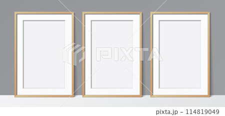 3 blank poster wooden frames leaning against a grey wall, vector mockup. 114819049