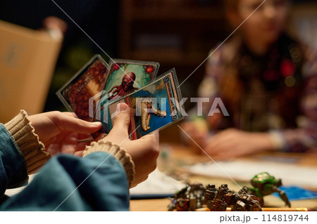 Child hands holding board game cards 114819744