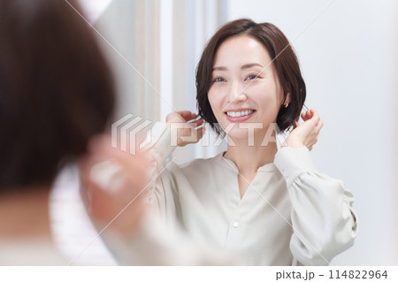 鏡を見て髪の毛を触るミドル女性(美容・ヘアセット・ヘアケア・髪の毛) 鏡を見て髪の毛を触るミドル女性(美容・ヘアセット・ヘアケア・髪の毛) 114822964