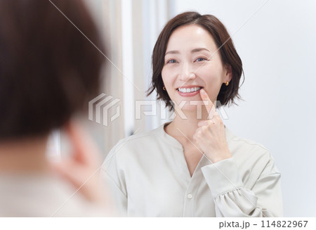 鏡を見て歯のチェックをするミドル女性（美容・歯列矯正・ホワイトニング） 114822967