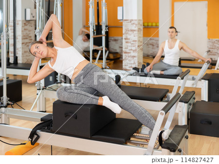 Girl in different poses performs static and dynamic exercises on reformer Girl in different poses performs static and dynamic exercises on reformer 114827427