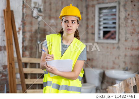 Female civil engineer making notes while controlling construction site Female civil engineer making notes while controlling construction site 114827461