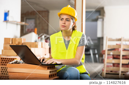 Woman with laptop on indoor construction site Woman with laptop on indoor construction site 114827616