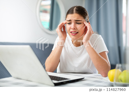 Girl with a headache complains to the doctor on the Internet using laptop Girl with a headache complains to the doctor on the Internet using laptop 114827960