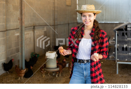 Happy girl standing in hen house with chicken eggs in hands 114828133