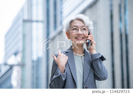 オフィス街でスマホを持つシニア女性 オフィス街でスマホを持つシニア女性 114829723
