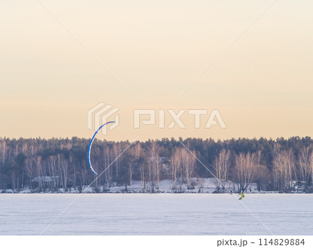 Kite surfer ride on snowboard. Snowkiting in the snow on frozen lake. 114829884