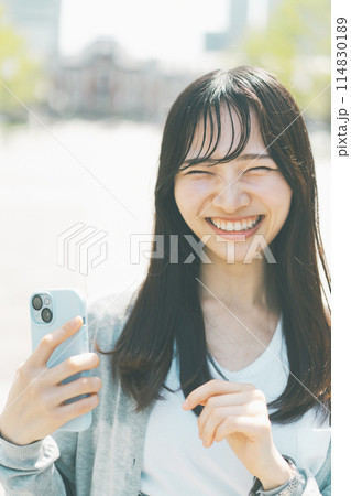 スマートフォンを持つ若い女性が笑っているシーン スマートフォンを持つ若い女性が笑っているシーン 114830189