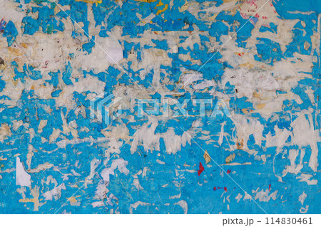Old wall painted in blue with peeled-off paper advertisements leftovers. Old wall painted in blue with peeled-off paper advertisements leftovers. 114830461