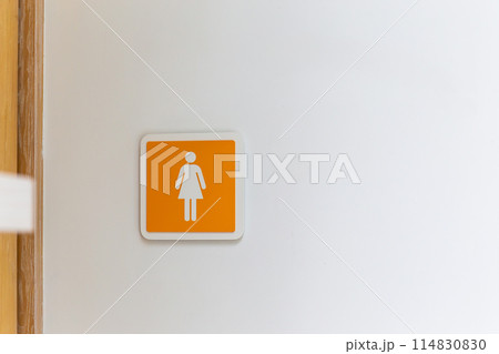 Orange female or woman toilet sign on the wall. copy space background Orange female or woman toilet sign on the wall. copy space background 114830830