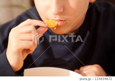 Caucasian person in navy blue t-shirt holding plate full of potato chips, young male eating potato chips Caucasian person in navy blue t-shirt holding plate full of potato chips, young male eating potato chips 114834672
