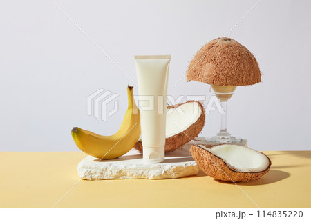 Unique template photo of tropical fruits theme, white blank label tube of cosmetic featured on a plaster podium, dry coconuts and banana decorated around. Mockup for design with vacant space for text Unique template photo of tropical fruits theme, white blank label tube of cosmetic featured on a plaster podium, dry coconuts and banana decorated around. Mockup for design with vacant space for text 114835220