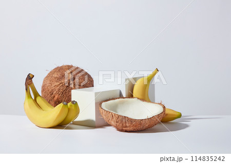 Two rectangular white empty platform in different size placed in the middle and surrounded by fresh banana and coconut on white minimal background. Copy space for text, front angle shot 114835242