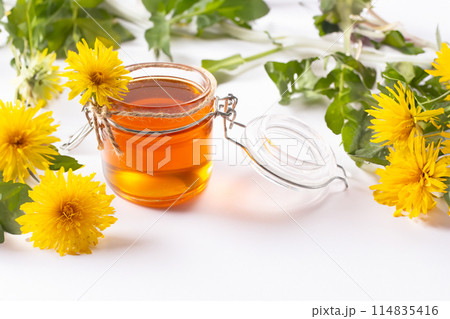 Dandelion honey and fresh flowers on white background. Close up Dandelion honey and fresh flowers on white background. Close up 114835416