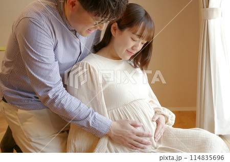 お腹の赤ちゃんをなでる夫婦 お腹の赤ちゃんをなでる夫婦 114835696