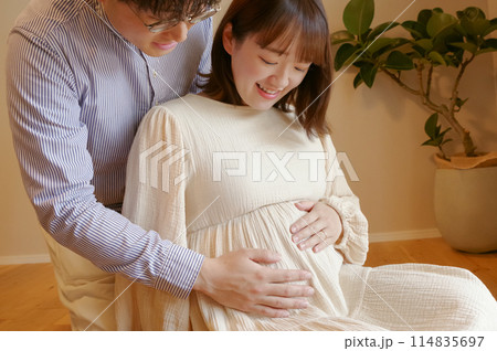 お腹の赤ちゃんをなでる夫婦 お腹の赤ちゃんをなでる夫婦 114835697
