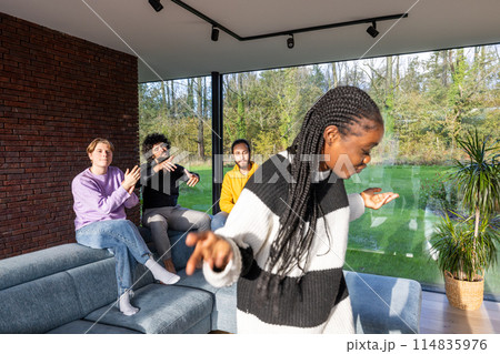 A woman dances in a living room, a group of people sit on a couch A woman dances in a living room, a group of people sit on a couch 114835976