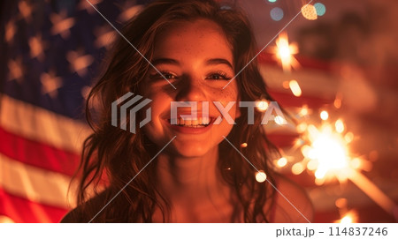 Young woman smiling, holding Bengal lights against American flag. Festive, patriotic atmosphere. 114837246