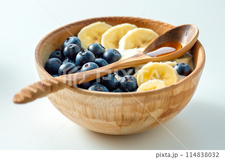 Blueberries, banana bites with greek yoghurt, granola and honey in bowl Blueberries, banana bites with greek yoghurt, granola and honey in bowl 114838032