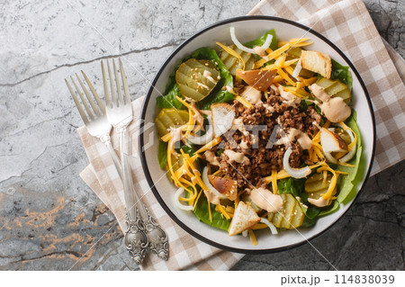 Cheeseburger, hamburger or burger keto salad with crunchy lettuce, creamy burger sauce, ground beef, pickles, cheese and onions closeup on the bowl. Horizontal top view 114838039