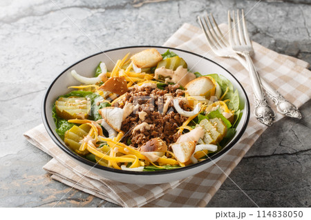 Homemade Cheeseburger Salad with lettuce, ground beef, pickles, cheddar cheese, onions and dressed with spicy sauce closeup on the bowl. Horizontal Homemade Cheeseburger Salad with lettuce, ground beef, pickles, cheddar cheese, onions and dressed with spicy sauce closeup on the bowl. Horizontal 114838050
