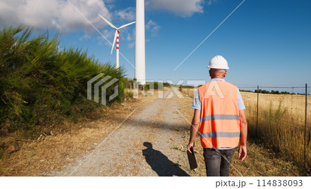 Engineer Walking Under Wind Turbines  114838093